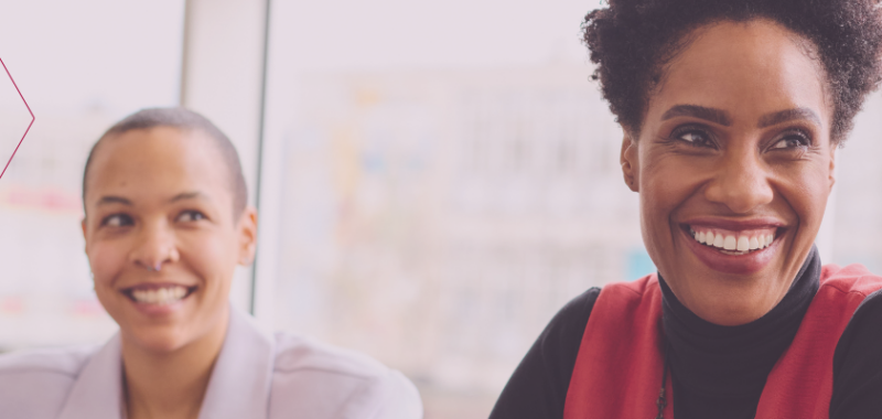 Zwei Frauen sitzen nebeneinander und lachen – Symbol für Austausch, Empowerment und Gemeinschaft im Projekt TakeOff. Deutsch üben und Job finden für Migrantinnen.