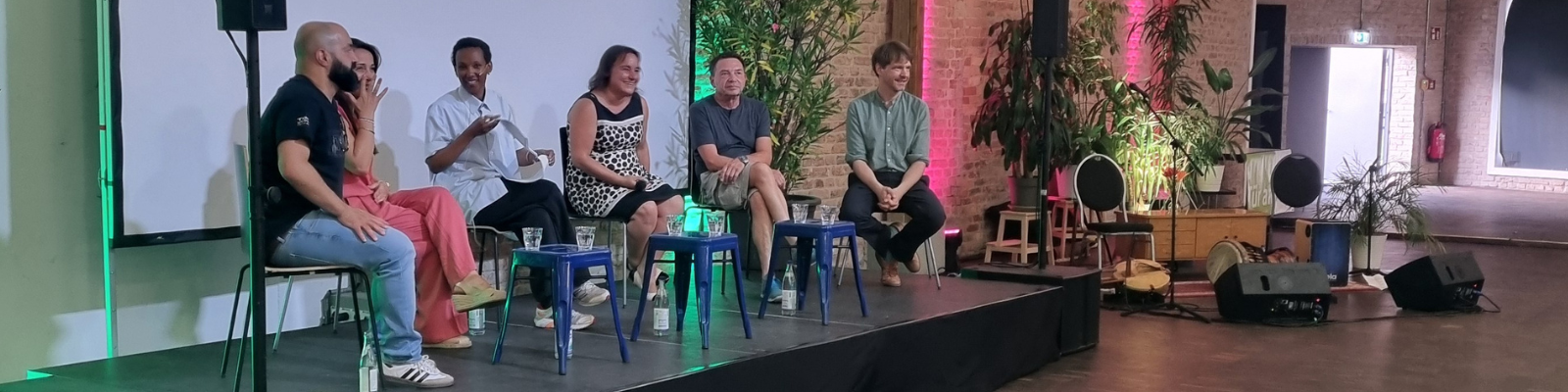 Podiumsdiskussion bei der Jubiläumsfeier von Tür an Tür – Integrationsprojekte gGmbH mit Tülay Ateş-Brunner, Stephan Schiele, Martina Wild, Hannes Schammann, Mohammad Sarhangi und Betiel Berhe auf der Bühne des Depot 29 in Augsburg.