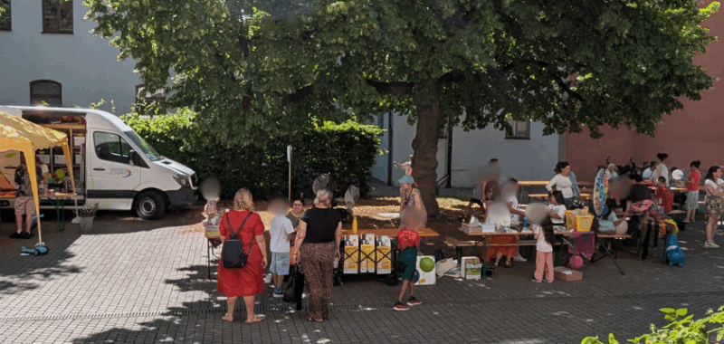 Besucher*innen und Kinder beim bunten Familienfest am Wollmarkt in Augsburg – organisiert vom Projekt TakeOff im Rahmen der Refugee Week 2025.