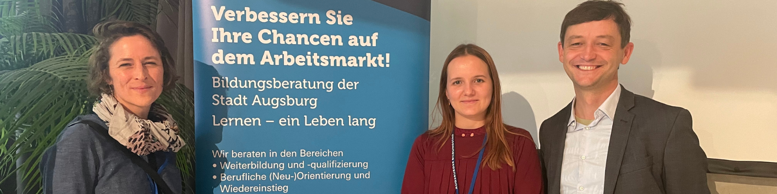 Andrea Bader und Rhea Darabos von Tür an Tür stehen zusammen mit Goran Ekmeščić von der Bildungsberatung Augsburg an einem Roll-up zur Fachtagung Digitales Bildungsmarketing und Inklusion in Augsburg