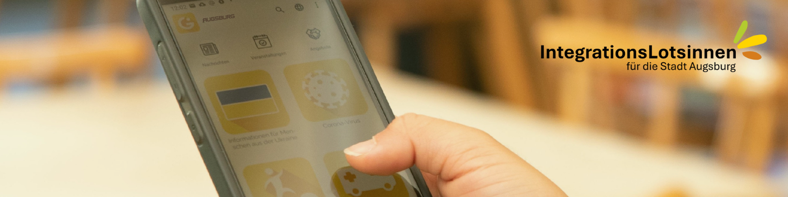 Hand hält Smartphone mit geöffneter Integreat-App – Symbol für digitale Hilfe bei Tür an Tür in Augsburg.